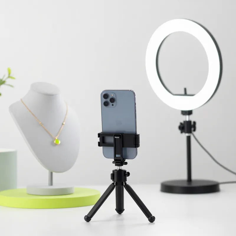 A phone on a tripod filming a necklace next to a ring light